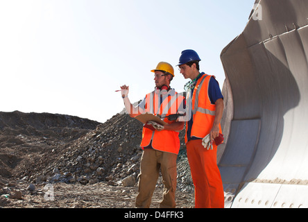 Workers talking by machinery in quarry Stock Photo