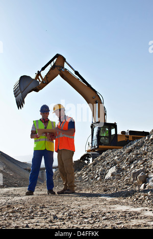 Workers talking by digger in quarry Stock Photo