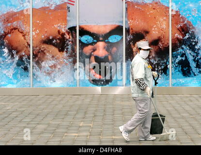 A sweeper with a pollution mask passes an advertising picture of US swimmer Michael Phelps prior to the 2008 Olympic Games, Beijing, China, 07 August 2008. Photo: Bernd Thissen ###dpa### Stock Photo