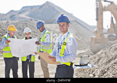 Businessmen reading blueprints in quarry Stock Photo