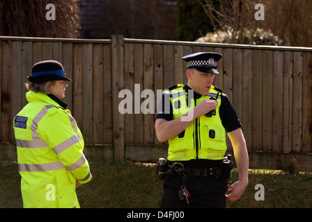 Police officer on phone and PCSO near scene of suspect arrested for threats to kill, Selborne, Hampshire, UK. Stock Photo