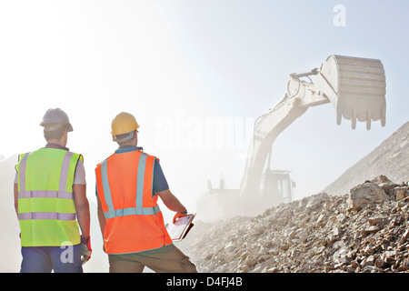 Workers watching digger in quarry Stock Photo