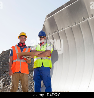 Workers smiling by machinery in quarry Stock Photo