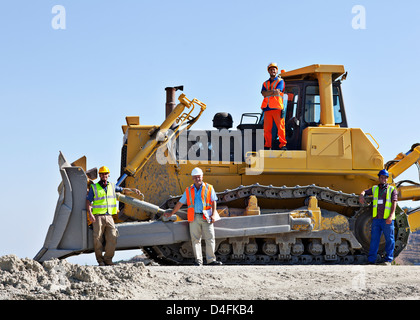 Workers on bulldozer smiling in quarry Stock Photo