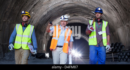 Businessman and workers walking in tunnel Stock Photo