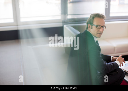 Businessman sitting in office lobby area Stock Photo