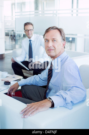 Businessmen sitting in office lobby area Stock Photo