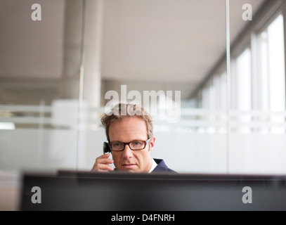 Businessman talking on phone at desk Stock Photo