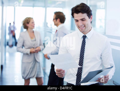 Businessman reading papers in office hallway Stock Photo