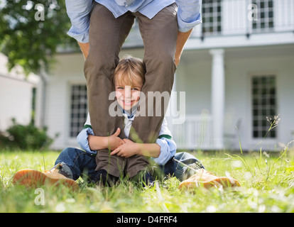 Boy peeking out from between father's legs Stock Photo