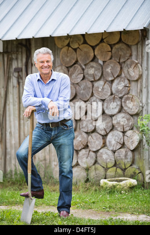 Man standing with shovel outdoors Stock Photo