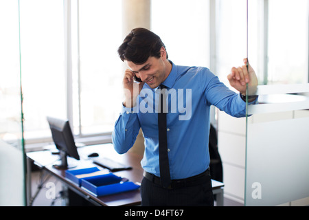 Businessman talking on cell phone in office Stock Photo