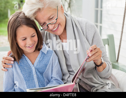 Woman and granddaughter reading on porch swing Stock Photo