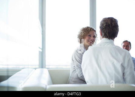 Business people sitting on sofa in office lobby Stock Photo