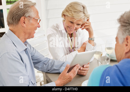Couple using digital tablet at table outdoors Stock Photo