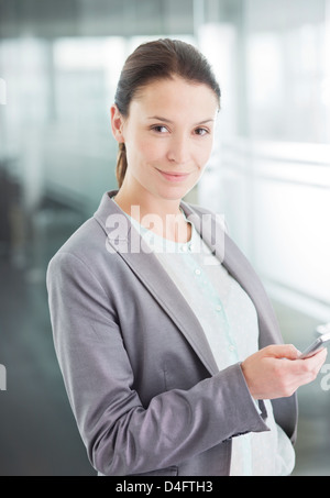 Businesswoman using cell phone in office Stock Photo