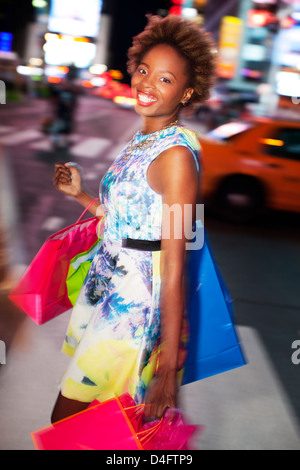 Woman carrying shopping bags on city street Stock Photo