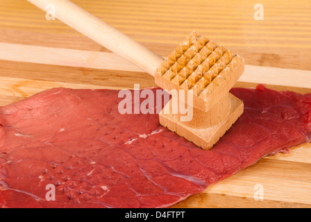 Hands tenderizing meat with a kitchen hammer Stock Photo
