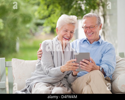 Couple using digital tablet together on porch swing Stock Photo
