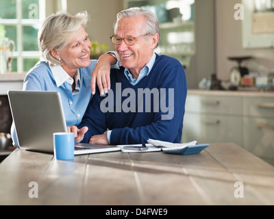 Couple using laptop at kitchen table Stock Photo