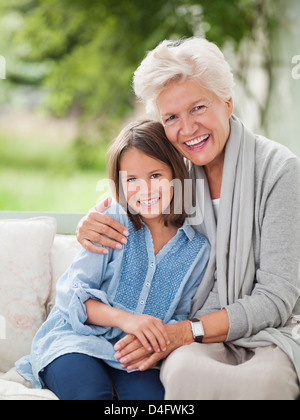 Woman and granddaughter smiling on porch swing Stock Photo