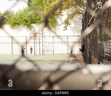 Man playing basketball on urban court Stock Photo