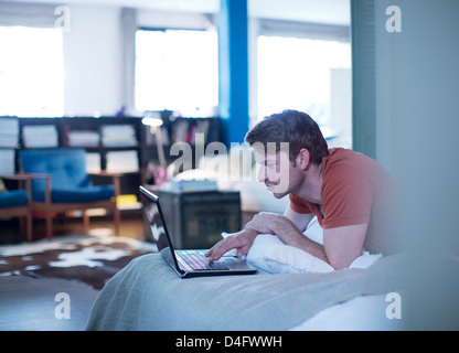 Man using laptop on bed Stock Photo