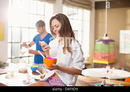 Woman using cell phone at breakfast Stock Photo