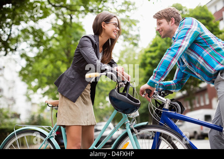 Couple pushing bicycles on city street Stock Photo