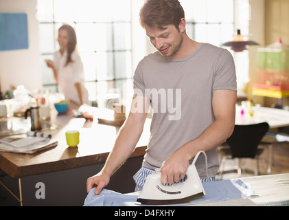 Man ironing shirt in kitchen Stock Photo