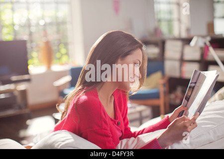 Woman reading magazine on sofa Stock Photo