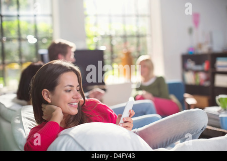 Smiling woman using cell phone on sofa Stock Photo