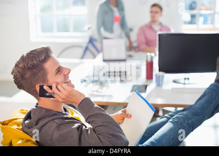 Businessman talking on cell phone in office Stock Photo