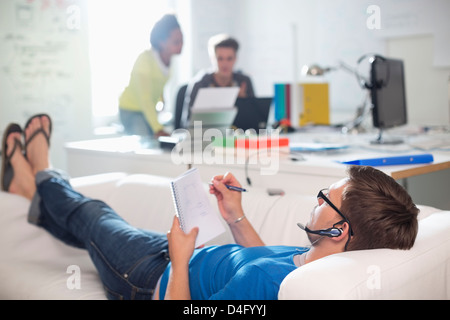 Businessman taking notes on sofa in office Stock Photo