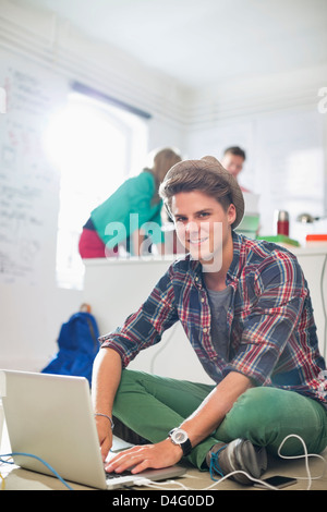 Businessman using laptop on floor in office Stock Photo