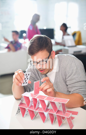 Businessman making house of cards in office Stock Photo