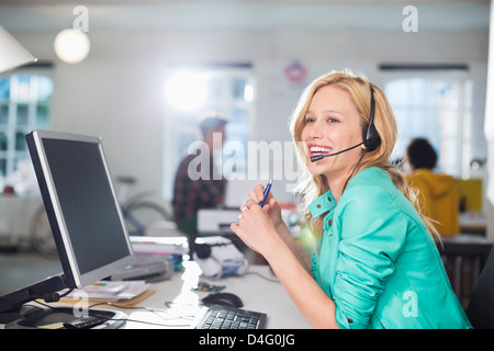 Businesswoman talking on headset at desk Stock Photo