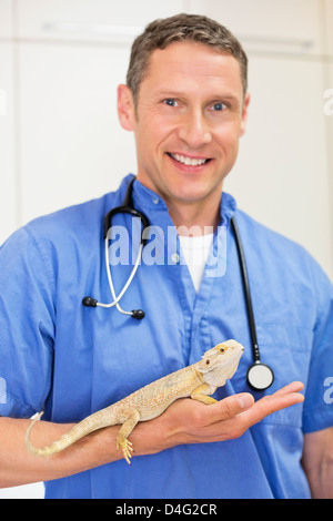 Smiling veterinarian holding lizard in vet's surgery Stock Photo