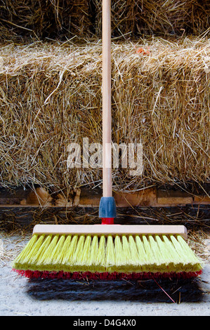 A sweeping brush rests beside some stacked hay bales Stock Photo