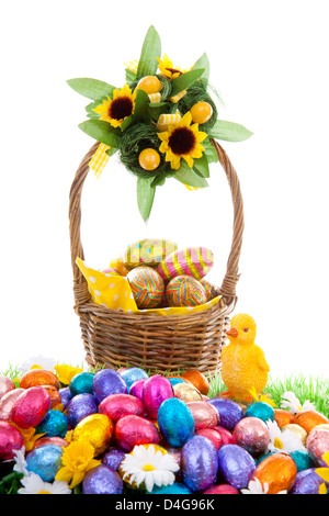 Colorful easter eggs, yellow chickens and basket on green grass with flowers Stock Photo