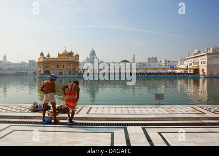 Two Sikh men at the Holy Pool inside the Golden Temple complex in Amritsar drying themselves after bathing in the sacred water Stock Photo