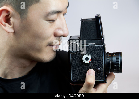 Young man taking photos with old-fashioned camera Stock Photo