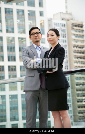 Asian businessman and businesswoman, standing on a walkway in Hong Kong. Stock Photo