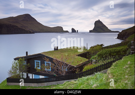 Traditional grass roofed house in the village of Bour, with views to Tindholmur, Vagar, Faroe Islands. Summer (June) 2012. Stock Photo