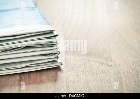 Plie of folded newspapers on a wooden surface Stock Photo