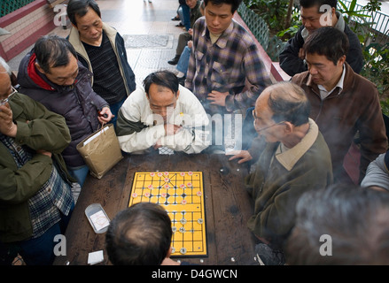 Two Chinese men playing Chinese Chess in the street, other men watching, Hong Kong, China Stock Photo