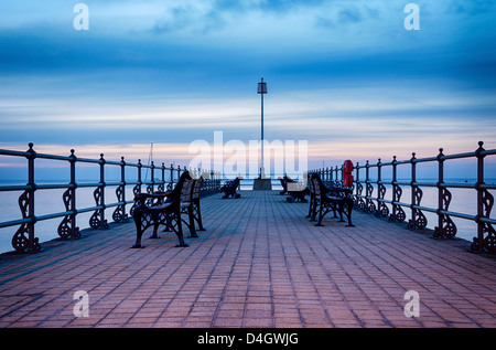 Summer sunrise and empty benches ot the Banjo Pier at Swanage in Dorset Stock Photo