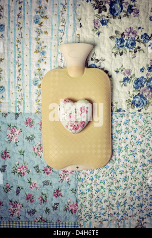 a hot-water bottle on a vintage bed with a floral heart Stock Photo