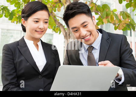 Happy young business partners using laptop outdoors Stock Photo