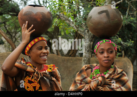 People, 2 beautiful young women, two Zulu maidens, traditional dress, balancing clay pots on head, Shakaland, South Africa, culture, friends Stock Photo